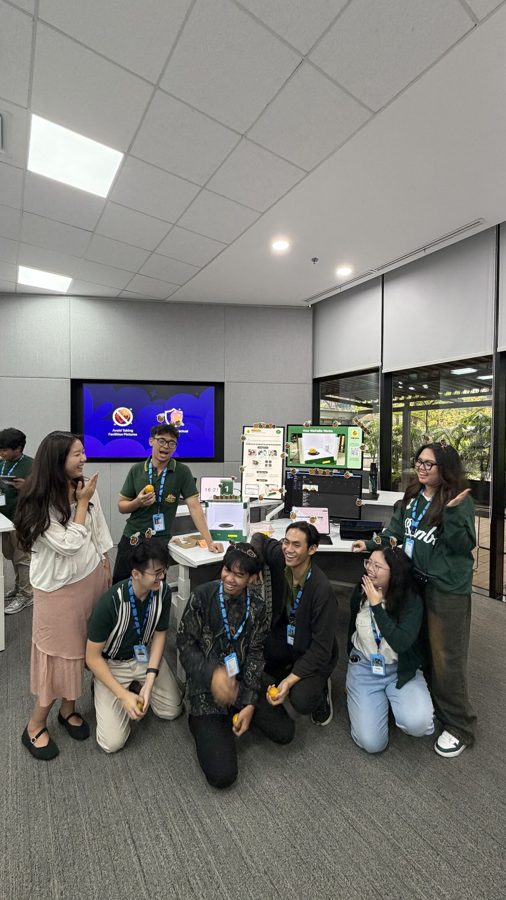 The team standing around the WaKaBe booth on demo day, holding oranges
